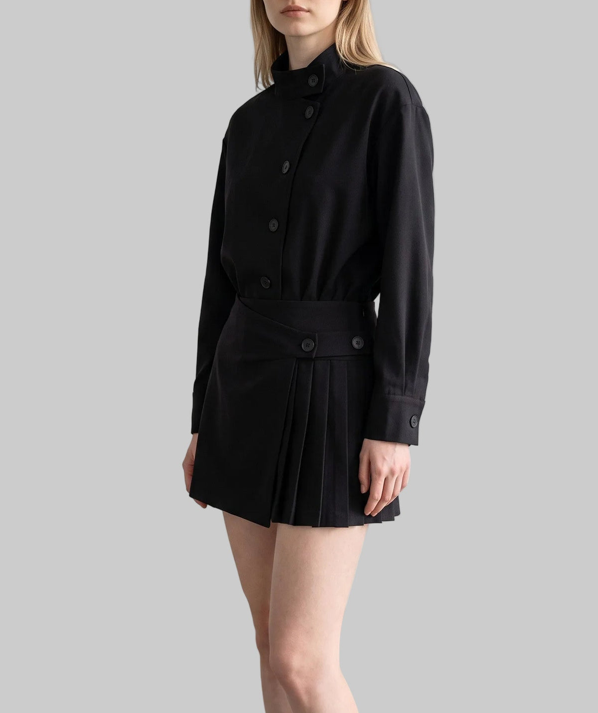 Model wearing the Celeste black belted shirt mini dress with long sleeves, button-front detailing, and a pleated mini skirt.