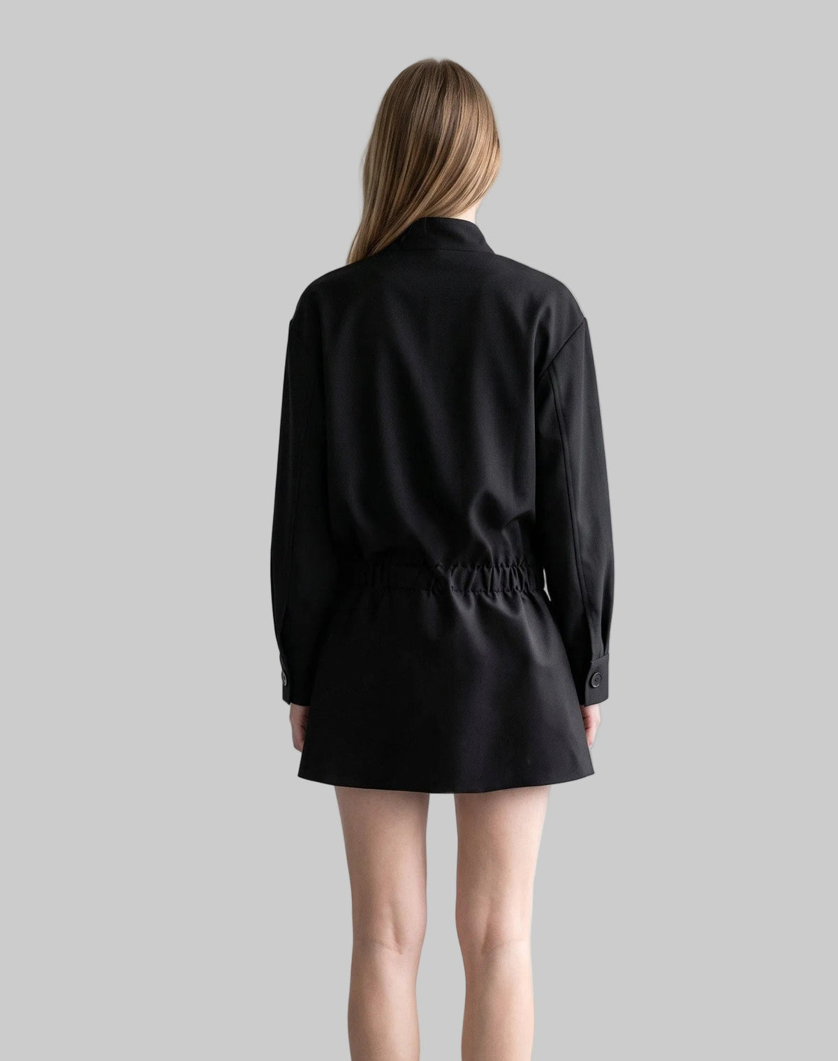 Model wearing the Celeste black belted shirt mini dress with long sleeves, button-front detailing, and a pleated mini skirt.