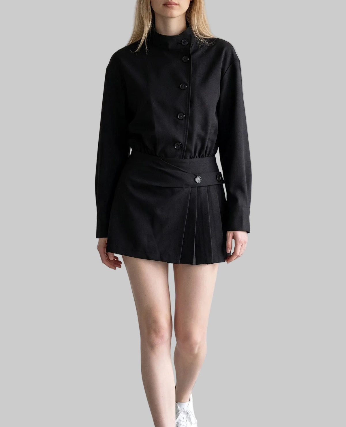 Model wearing the Celeste black belted shirt mini dress with long sleeves, button-front detailing, and a pleated mini skirt.