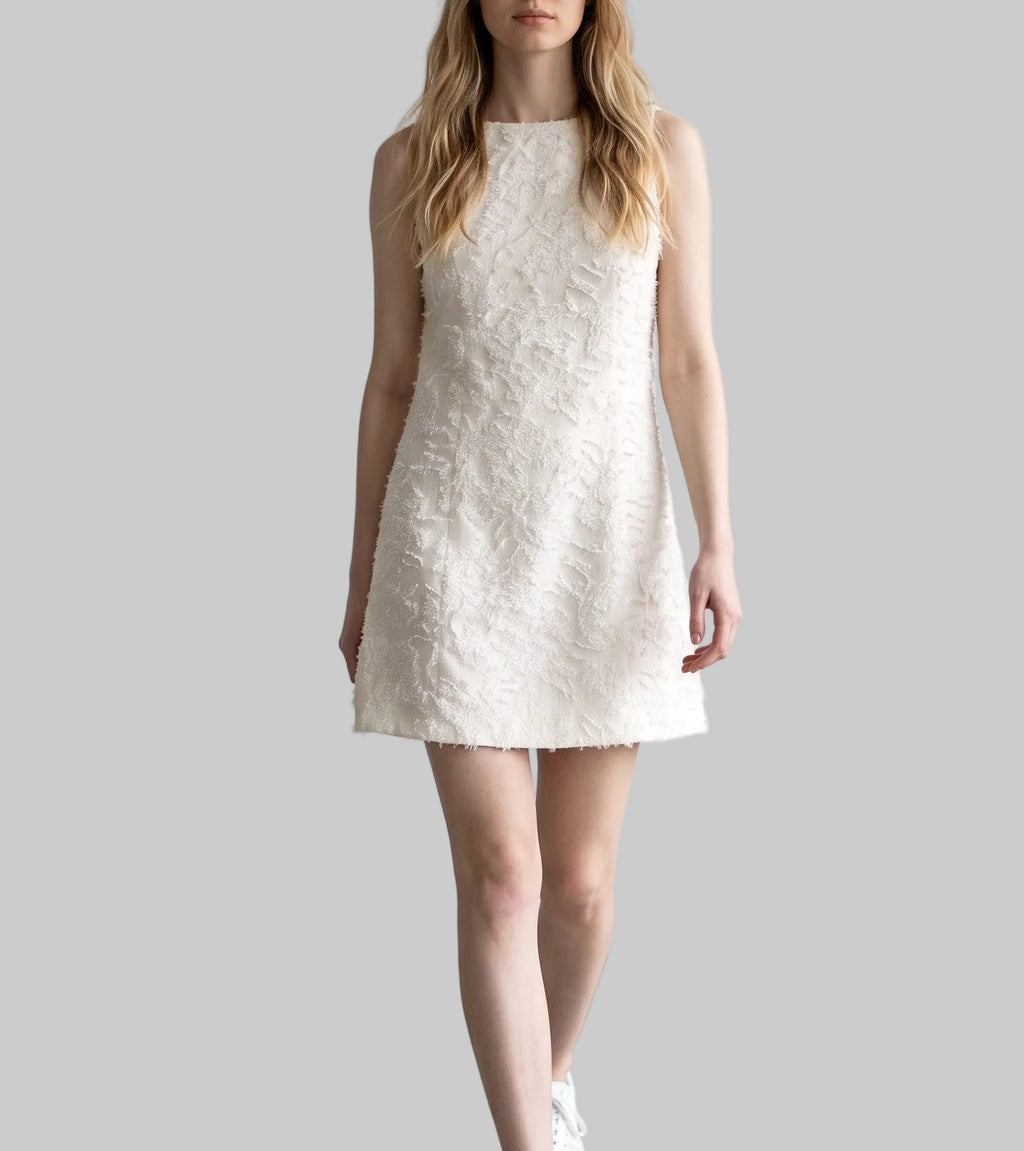 Model wearing the Lucia ivory jacquard mini dress with textured floral fabric and gold-tone shoulder details