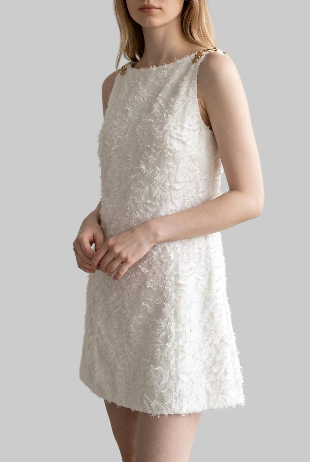 Model wearing the Lucia ivory jacquard mini dress with textured floral fabric and gold-tone shoulder details