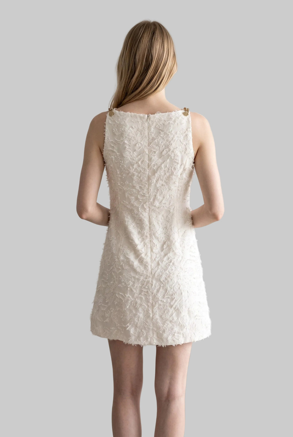 Model wearing the Lucia ivory jacquard mini dress with textured floral fabric and gold-tone shoulder details