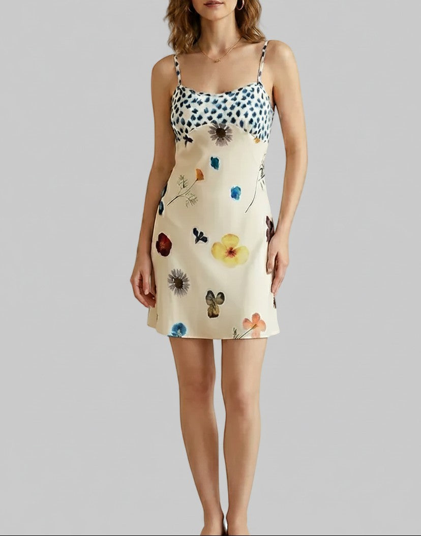 LUNRIA ivory cami slip mini dress featuring colorful floral and butterfly prints, blue patterned detailing, and delicate spaghetti straps.