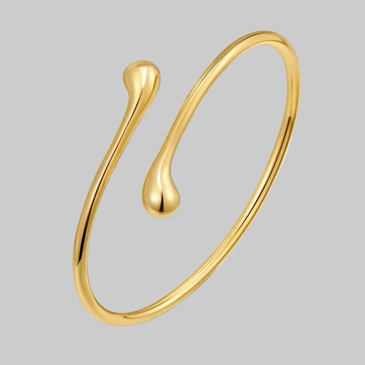 LUNRIA gold teardrop open arm cuff featuring a minimalist sculptural design worn on the upper arm.