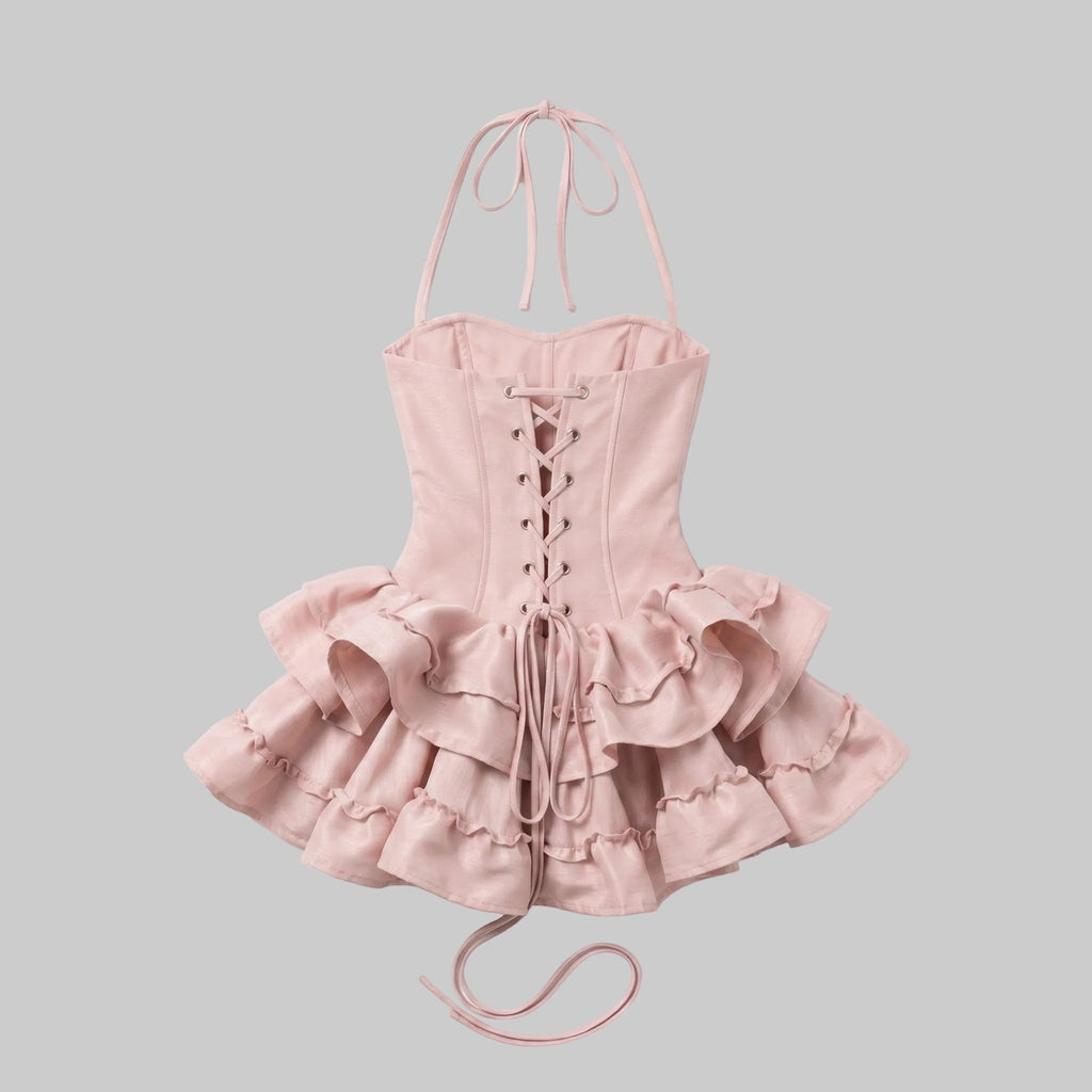 Blush pink halter corset mini dress with bow detail, structured waist, lace-up back, and layered ruffle skirt.