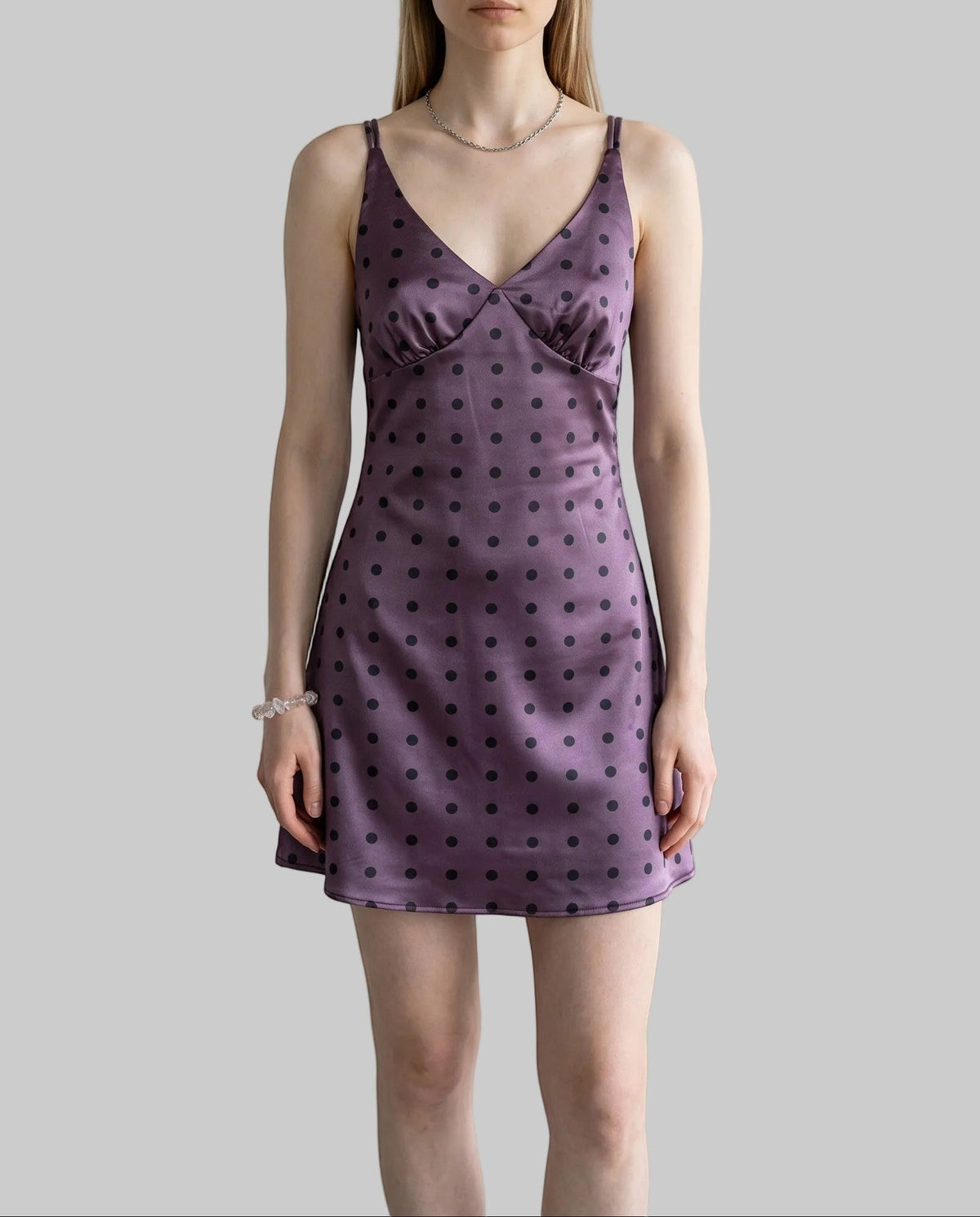 Purple polka dot satin mini dress with a V-neckline, fitted silhouette, crisscross straps, and lace-up back.