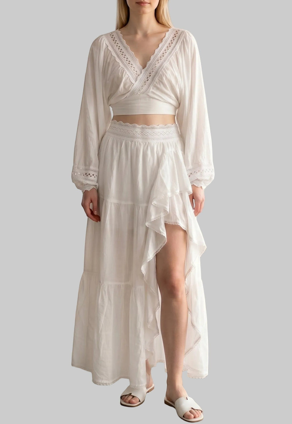 White two-piece set with a balloon sleeve wrap crop top, lace trim, and an asymmetrical ruffle maxi skirt.