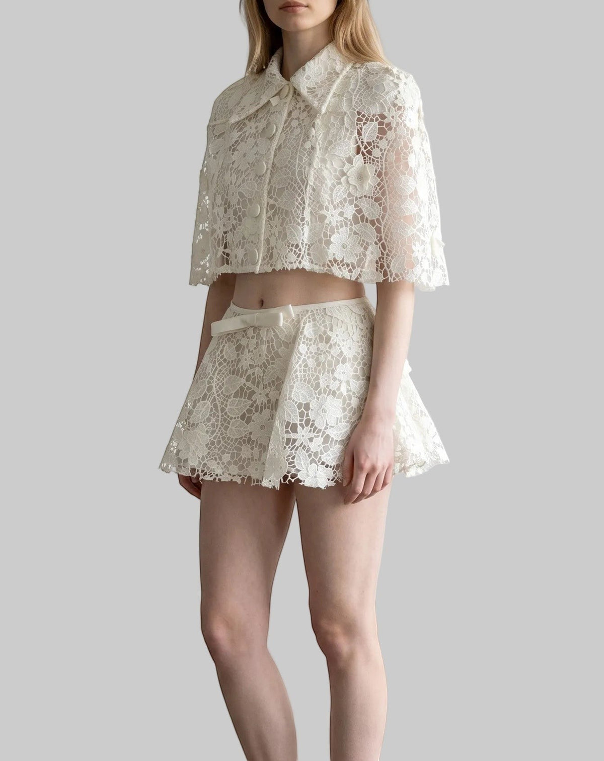 White floral lace crop top and matching shorts set with a collared button-front design and bow detail.