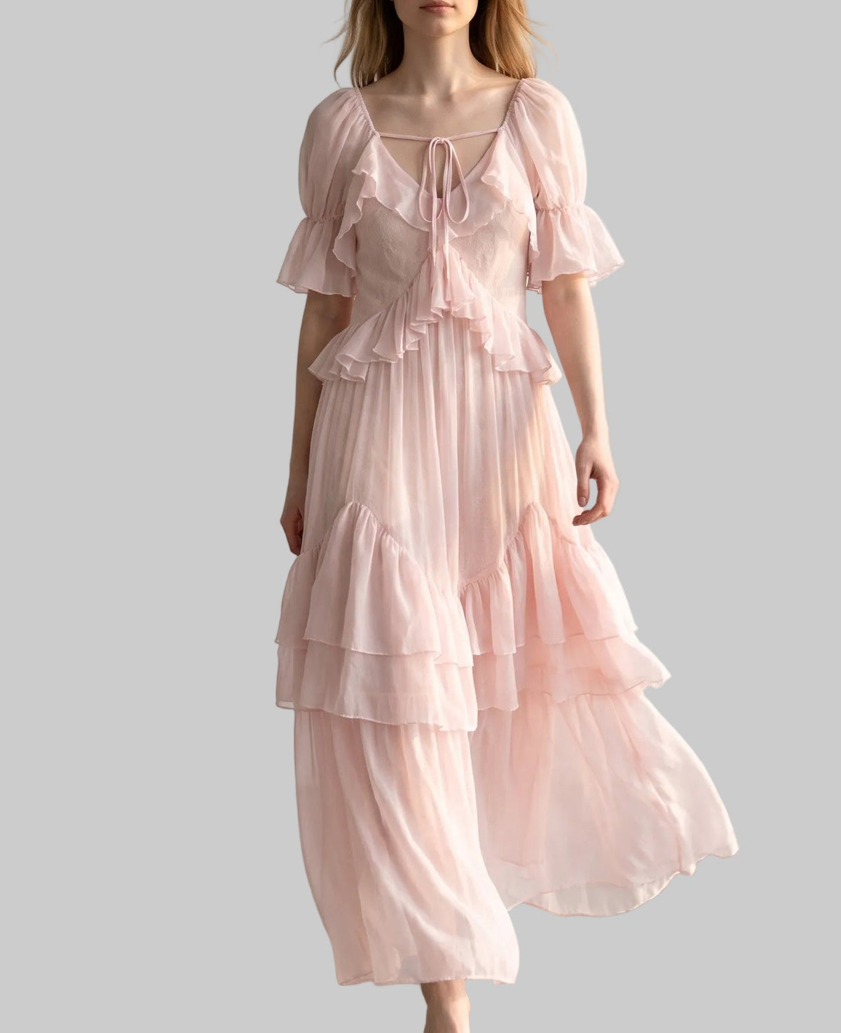Model wearing the Rosalie pink ruffle maxi dress with tiered skirt, ruffle sleeves and bow details